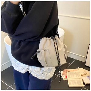 Detail of beige drawstring bucket bag featuring durable nylon and mesh side pockets
