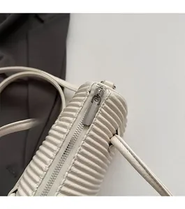 Close-up of minimalist silver zipper and pleated texture on an off-white chic crossbody bag
