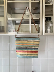 Colorful striped woven bucket bag with brown leather shoulder strap in a casual style