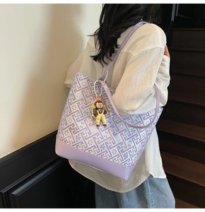 Detailed view of large purple tote bag with geometric weave and doll charm on model
