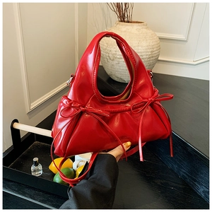 Detailed close-up of a glossy red fashion handbag with stylish symmetrical bow accents