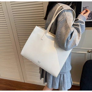 Side view of a white large capacity tote bag with litchi grain texture on model shoulder