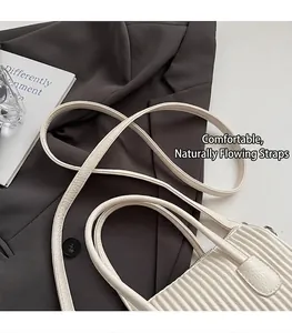 Detail of cream pleated leather handbag featuring adjustable strap and smooth handle