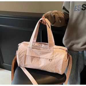 Close-up of a pink travel bag on a leather seat with reinforced handles and textures