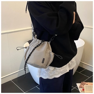 Detail of grey nylon bucket bag featuring a woven drawstring and mesh side pocket