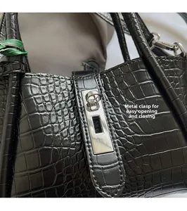 Detail of silver twist lock and crocodile texture on black leather handbag