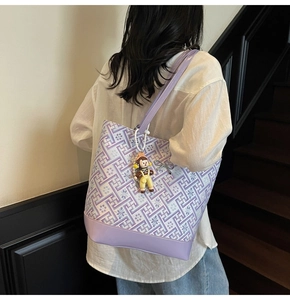 Detail of purple geometric tote bag with matching leather bottom and cute doll pendant