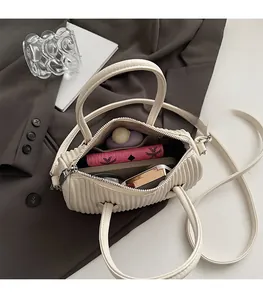 Interior view showing spacious main compartment and side pocket of cream crossbody bag