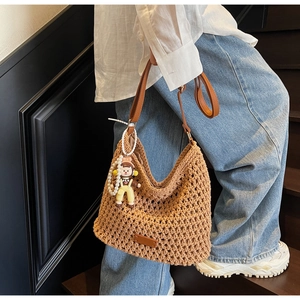 Detail of woven beach tote featuring brown leather strap and cute pearl doll pendant
