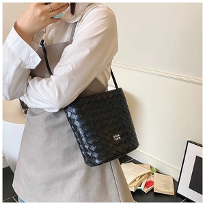 Close-up of a black woven texture bucket bag with metal logo and slim crossbody strap
