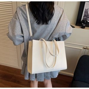 Detailed view of a white large tote bag with lychee texture and adjustable strap on a model