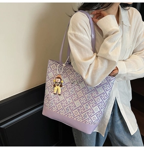 Detailed close-up of a vintage pattern tote bag with purple leather trim and doll pendant