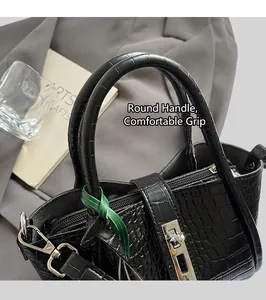 Detail of black crocodile texture handbag featuring silver twist lock and rounded handle