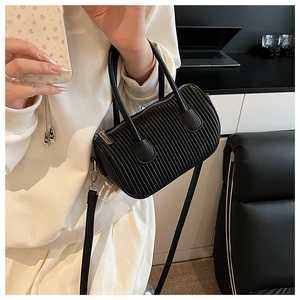 Detail shot of black pleated cylinder bag with silver hardware and shoulder strap