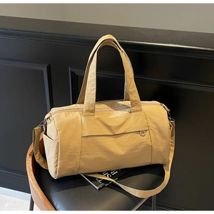 Detail of khaki nylon travel bag with wide handles and adjustable strap on a chair