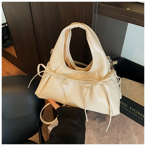 Detail of cream PU leather handbag featuring elegant bows and integrated handle design