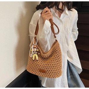 Close-up of brown crochet tote bag with leather strap and cute doll charm pendant