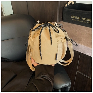 Detail of khaki nylon bucket bag with striped drawstring and side mesh pocket