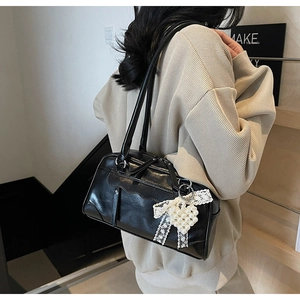 Détail du sac porté épaule noir avec nœud en dentelle et pendentif cœur en perles blanches