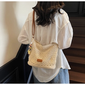 Detail of cream crochet shoulder bag featuring leather strap and cute monkey charm