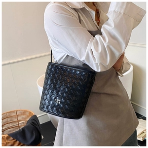 Detail of black woven leather bucket bag with silver logo on casual model outfit