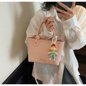Pink woven bucket bag featuring cute cartoon doll charm and leather top handle detail