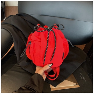 Detail of red nylon drawstring bucket bag featuring mesh pocket and woven cord closure