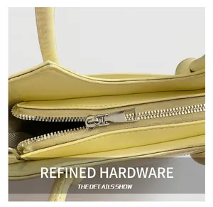 Close-up of high-quality silver metal zipper and neat stitching on light yellow bucket bag