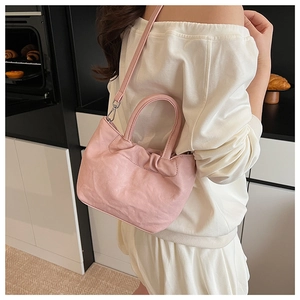 Side view of pink pleated cloud bag worn by a model in a minimalist kitchen setting