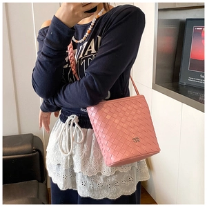 Detailed pink woven bucket bag with metallic logo and detachable leather shoulder strap