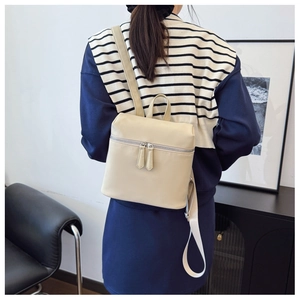 Rear view of model wearing a creamy beige mini PU leather backpack with silver zippers
