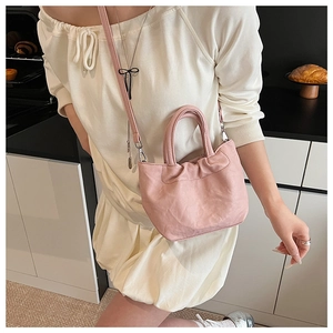 Chic pink pleated bucket bag shown on a model in a minimalist home setting for daily wear