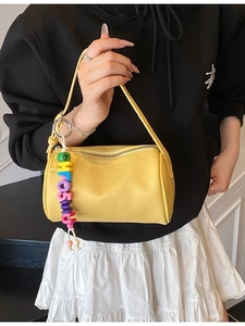Yellow cylindrical crossbody bag in lychee pattern leather with alphabet bead charm