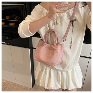 Detail view of pink pleated bucket bag showing soft leather texture and silver buckle