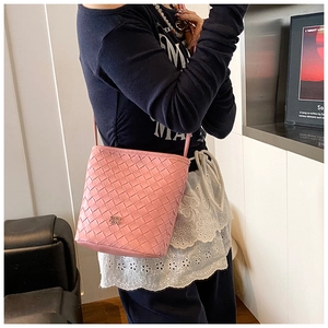 Detail showing the pink woven texture and metal logo of this casual crossbody bucket bag