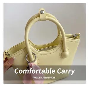 Macro detail of yellow leather handbag showing sturdy handles and pink decorative scarf