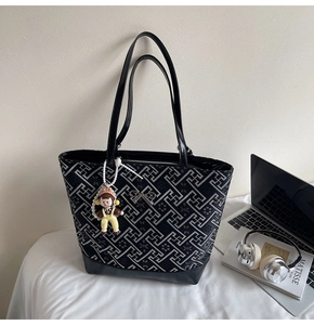 Detail of black and gray geometric tote bag with metal bow and cartoon charm ornament