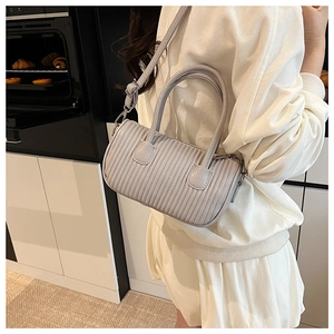 Detailed view of grey ruched cylinder bag with adjustable strap in a modern kitchen setting
