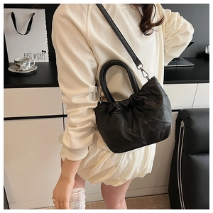 Close-up of black pleated bucket bag with silver hardware and detachable strap