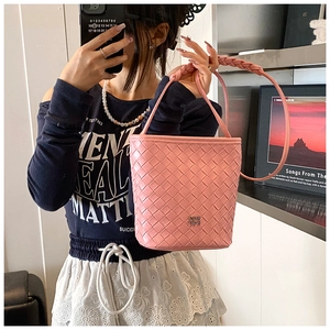 Close-up of pink woven bucket bag texture with metallic logo and braided handle strap