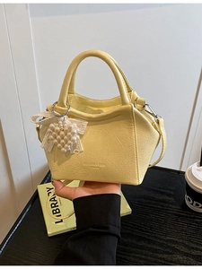 Borsa a secchiello giallo chiaro con texture litchi, ciondolo di perle e tracolla