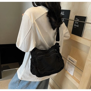 Detail of black canvas messenger bag with double zippers and adjustable strap