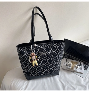 Detail of black geometric tote bag with silver bow accent and cute cartoon charm