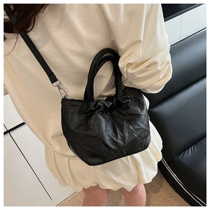 Detail of black pleated bucket bag showing premium leather texture and silver hardware