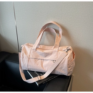 Detailed view of pale pink nylon travel bag with adjustable strap and smooth texture