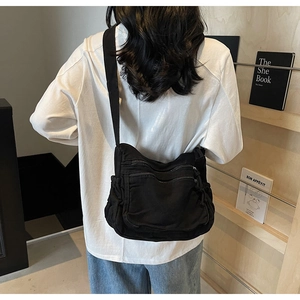 Detailed view of the multi-pocket black canvas crossbody bag with adjustable wide strap