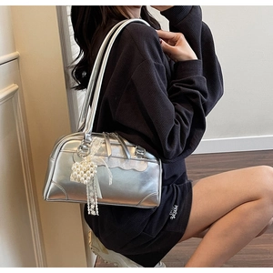 Detail of silver metallic handbag featuring wave lace edges and a pearl cluster charm