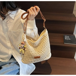 Beige crochet woven shoulder bag with brown leather strap and cartoon doll charm detail