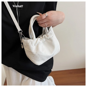 Detail of white pleated bucket bag with textured faux leather and round handles