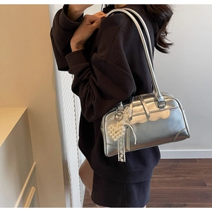 Détail du sac à bandoulière argenté avec breloque cœur en perle et ruban de dentelle